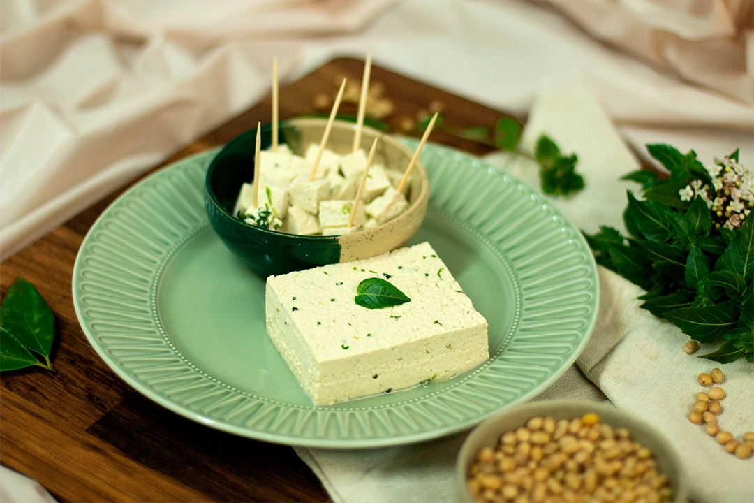 Bloc de tofu au basilic présenté dans une assiette, décoré avec du basilic